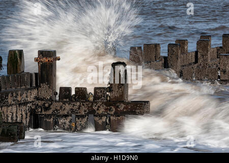 Meerwasser bricht durch Buhnen am Strand in Zeitlupe Stockfoto