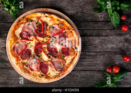 Köstliche frische Peperoni-Pizza mit Salami, Speck, Paprika, Frühlingszwiebeln und Käse auf dem hölzernen Hintergrund. Ansicht von oben. Stockfoto