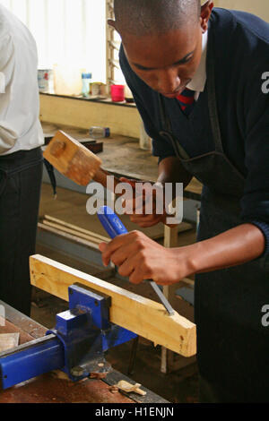 Schuljunge Meißeln mit Hammer in Holzarbeiten Klassenzimmer, Markus Schule, Mbabane, Hhohho, Königreich Swasiland Stockfoto