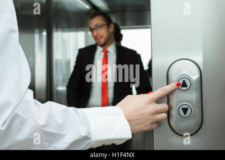 Weibliche Hand drücken Lift up-Taste. Geschäftsmann in den Aufzug. Stockfoto
