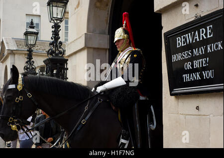 Berittene Soldaten des berittenen Regiments der Haushaltscharde, die vor dem Museum der Hauswächter Dienst haben. Schild sagt: „Vorsicht Pferde können treten oder beißen!“ Stockfoto