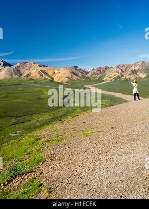 Ein weiblicher Touristen genießt ihre Sicht des Polychrome Becken, Denali-Nationalpark, Alaska. Stockfoto