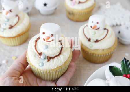 Hand halten Spaß hausgemachte schmelzen Schneemann-Muffins für Kinder Stockfoto