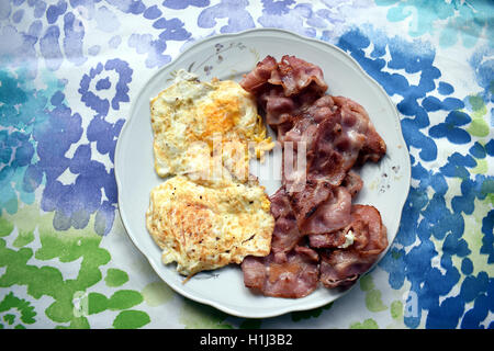 Spiegeleier und Speckscheiben auf einem weißen Teller. Stockfoto