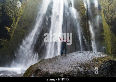 Wanderer auf Felsen vor Gljúfrabúi Wasserfall in Hamragardar, Region Süd, Island Stockfoto