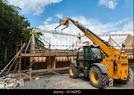 Wohnungsbau, UK. Mit Hilfe einer JCB 535-95 Loadall Teleskop Stapler die Firstpfette auf ein neues Haus zu installieren Stockfoto