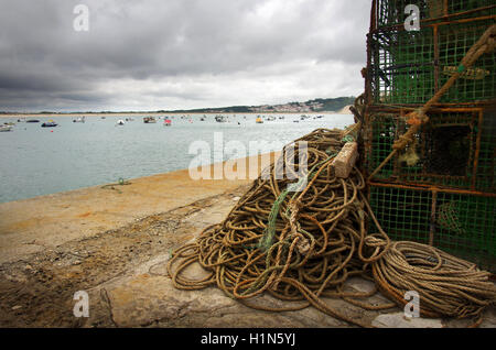 Stapel von Fischerei fallen und Seile in einem Pier und verankerte Boote auf dem Meer Stockfoto