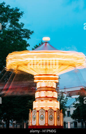 Bewegungsunschärfe Effekt um von hell beleuchteten rotierenden Hochgeschwindigkeits Karussell Karussell. Sommerabend In der Stadt Amuseme Stockfoto