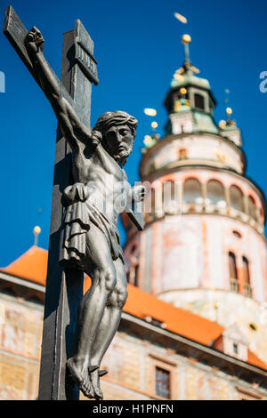 Die Statue des gekreuzigten Christus am Kreuz auf der Lazebnicky die meisten Brücke auf einem Hintergrund von einem alten Schlossturm In Cesky Kr Stockfoto