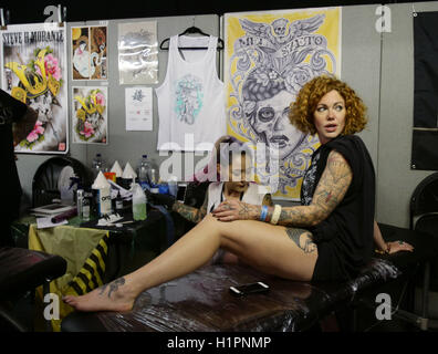 Eine Frau, die eine Tätowierung getan während der London International Tattoo Convention in Tobacco Dock in London. Stockfoto