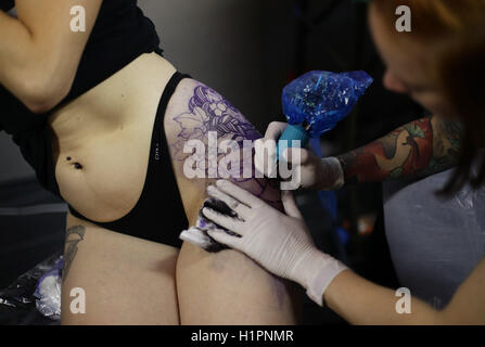 Eine Frau, die eine Tätowierung getan während der London International Tattoo Convention in Tobacco Dock in London. Stockfoto