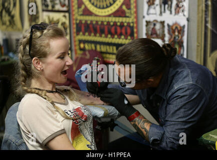 Eine Frau, die eine Tätowierung getan während der London International Tattoo Convention in Tobacco Dock in London. Stockfoto