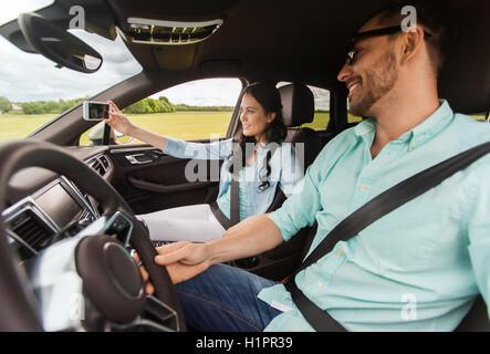 glückliches Paar fahren im Auto und nehmen selfie Stockfoto