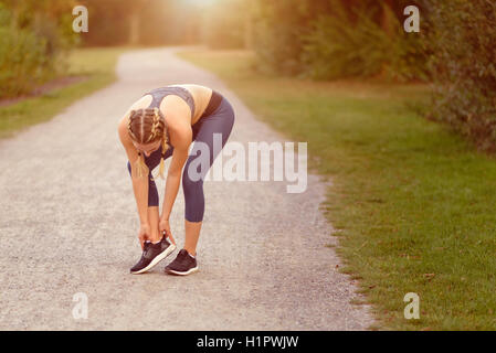 Junge Frau vor dem Training, Übungen Übungen, dehnen sie Muskeln auf einem Feldweg im Morgenlicht Stockfoto