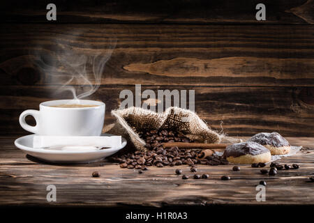 Tasse Kaffee und Kaffeebohnen auf dem hölzernen Hintergrund. Stockfoto