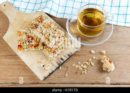 Knusprige Körner Müsliriegel oder Reis Kekse mit einer Glastasse heißen Tee auf Holztisch. Stockfoto