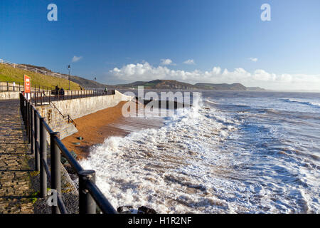 Sturm-Wellen auf den Strand und gegen den neuen Deich in Lyme Regis mit Golden Cap hinaus, Dorset, England, UK Stockfoto