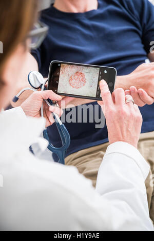 Arzt mit seinem Handy, um medizinische Daten zu übertragen. Stockfoto