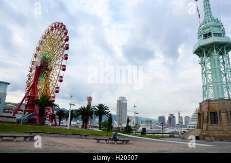 Thai Frau im Park zwischen Leuchtturm und Riesenräder mit klassischen Gebäude und Wahrzeichen Kobe Port Tower am Kob Stockfoto