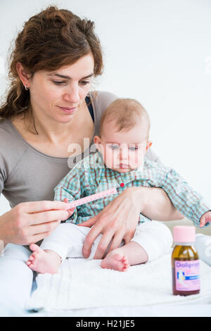 Mutter gibt ihr 6 Monate altes Baby Mädchen Doliprane mit einer Pipette. Stockfoto