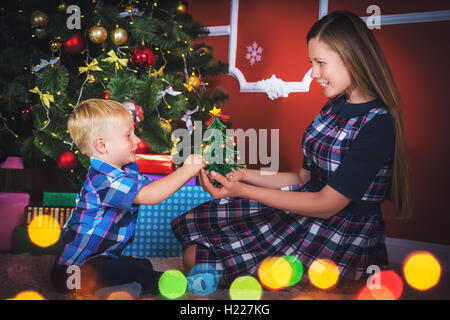 Die junge Mutter und ihr Sohn in der Nähe von einem Weihnachtsbaum im Zimmer mit Geschenken. Stockfoto