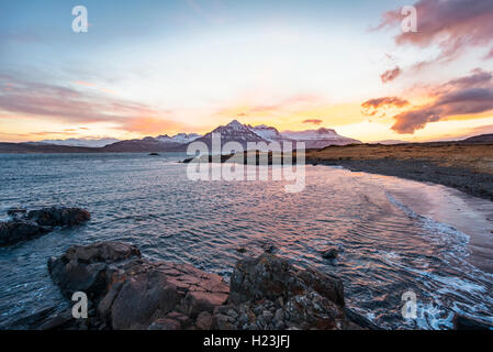 Sonnenuntergang über schneebedeckte Berge, schwarzen Strand in Berufjörður Fjord, Region Ost, Island Stockfoto
