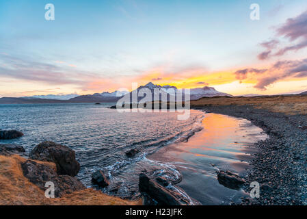 Sonnenuntergang über schneebedeckte Berge, schwarzen Strand in Berufjörður Fjord, Region Ost, Island Stockfoto