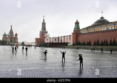 Moskau, Russland. 22. Sep, 2016. Touristen posieren für Erinnerungsfotos in ein herbstlicher Nieselregen neben der Kreml-Mauer auf rot Sqare vor der Kulisse der Basilius-Kathedrale (l) in Moskau, 22. September 2016. Foto: SOEREN STACHE/Dpa/Alamy Live News Stockfoto