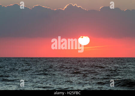 Wetter, Sonnenaufgang über dem Meer, Englischer Kanal bei Broadstairs. Roter Himmel mit Sonne über hinter Cloud nach steigenden verschwinden. Stockfoto