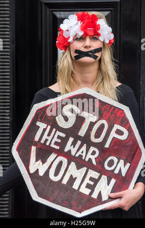 London, UK. 24. Sep, 2016. Ein polnischer feministische steht mit ihrem Mund versiegelt mit schwarzem Klebeband mit einem Schild "Stop Krieg gegen Frauen" bei der Protest in der polnischen Botschaft in Solidarität mit der 5. jährlichen März zur Wahl in Irland gegen die strengen Anti-Abtreibung Gesetze es verurteilt von der UNO als "grausame, unmenschliche und erniedrigende". In Polen MPs in das konservative Recht und Gerechtigkeit (PiS) Partei unterstützen einen Gesetzentwurf vorgelegt von der Lobby der Abtreibung zu stoppen, die Abtreibungen außer wo das Leben der Mutter gefährdet geahndet wird, 3 bis 5 Jahre im Gefängnis war machen würde. Bildnachweis: Peter Marshall/Alamy Live Ne Stockfoto