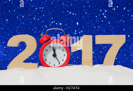 Frohes neues Jahr 2017 Grußkarte. Wecker und die Zahlen 2017 in einer Schneewehe auf einem blauen Glitzer-Hintergrund Stockfoto