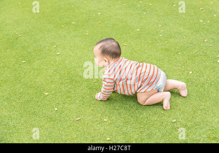 Outdoor Portrait asiatische Babyjungen spielen sitzen und krabbeln auf der grünen Wiese im park Stockfoto