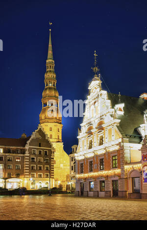 Nacht Blick auf Haus der Schwarzhäupter und St. Peter Kirche in Riga, Lettland. Das Schwarzhäupterhaus wurde ursprünglich im 14. Jahrhundert und die Kirche wurde erstmals im Jahr 1209 erwähnt. Stockfoto