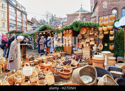 Riga, Lettland - 25. Dezember 2015: Alte lettische Dame betrachten die Strohkörbe an einem der Stände während des Weihnachtsmarktes in Riga. Der Markt ist voll von verschiedenen festlichen Souvenirs und waren. Stockfoto