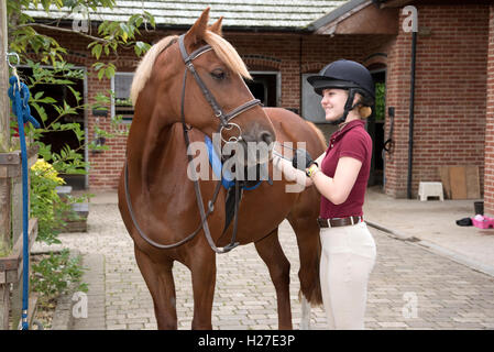 Junge Fahrer ein Pony für ihre Reitstunde vorbereiten. Teenager die Steigbügel Längeneinstellung Stockfoto