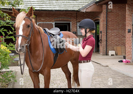 Junge Fahrer ein Pony für ihre Reitstunde vorbereiten. Teenager die Steigbügel Längeneinstellung Stockfoto