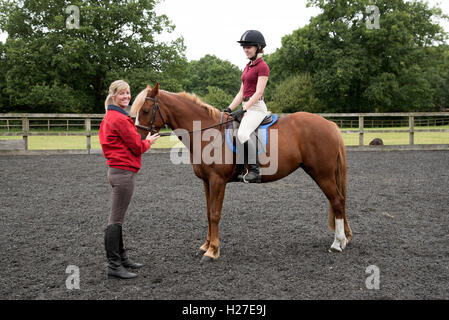 Junges Pony Reiter im Sattel sitzen. Der Teenager Schüler lernen, mit dem Lehrer zu reiten Stockfoto