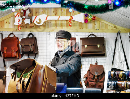 Vilnius, Litauen - 27. Dezember 2015: an einem der Stände Mann verkauft Ledertaschen während des Weihnachtsmarktes in Vilnius. Die Messe findet jedes Jahr von Dezember bis Anfang Januar. Stockfoto