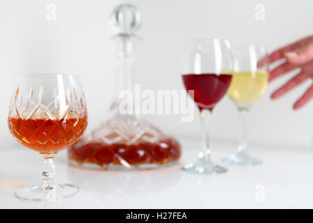 Nicht identifizierter Hand greift nach Weinbrand oder Cognac in geschliffenem Glas Becher mit Dekanter mit weiß- und Rotwein Stockfoto