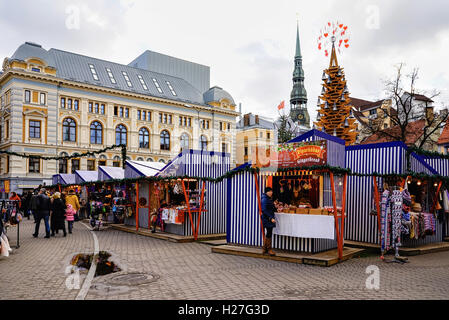 Riga, Lettland - 26. Dezember 2015: Menschen auf dem Weihnachtsmarkt Markt mit St. Peter Church Turm befindet sich auf dem Livu-Platz im Zentrum der Altstadt von Riga, Lettland. Stockfoto