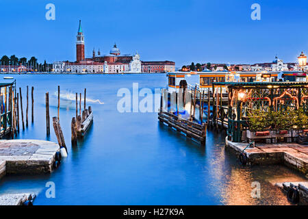 Blaues Wasser in Venedig Canal in der Nähe von Piazza San Marco in Richtung Kirche San Giorgio Maggiore über Canal bei Sonnenuntergang. Stockfoto