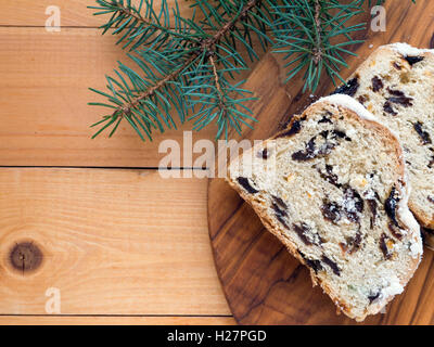 Christstollen Deutsch Weihnachtskuchen auf die strukturierte Holz Brett und Blaufichten Zweige auf den Holzplanken Stockfoto