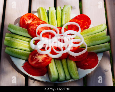 Teller mit Salat aus frischen in Scheiben geschnittenen Gurken, Tomaten und weiße Zwiebeln Stockfoto