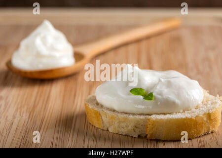 Frisches Brot mit cremigen Ausbreitung und Kräutern auf hölzernen Hintergrund Stockfoto