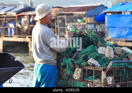 Nha Trang, Vietnam - 22. Oktober 2011: Ein Fischer sein Fischernetz für einen neuen Arbeitstag auf einen lokalen Hafen bereitet Stockfoto