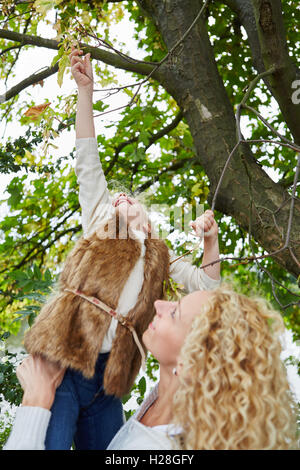 Mutter Kind Kommissionierung Blätter vom Baum im Herbst im park Stockfoto