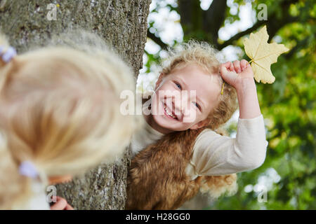 Zwei Kinder spielen verstecken und suchen im Park im Herbst Stockfoto