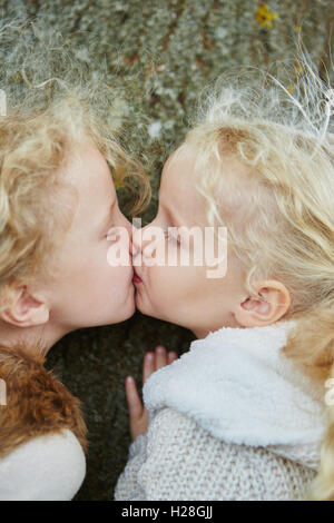 Zwischen zwei kleinen Schwestern zu küssen, als Zeichen der Geschwister lieben und Liebe Kinder Stockfoto