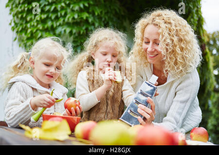 Familie mit Kindern peeling Äpfel als Teamarbeit im Garten Stockfoto