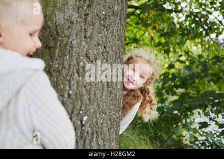 Zwei Mädchen spielen verstecken und suchen im Herbst im park Stockfoto